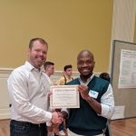 color photo of TJ Greenier accepting a certificate of appreciation from a grad student at UMD iSchool